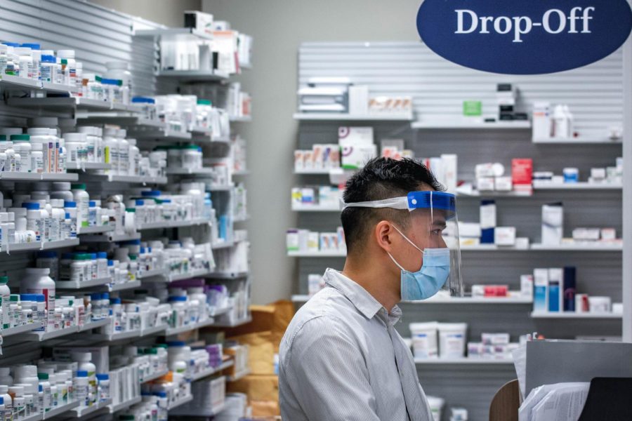 A pharmacist assists customers during the pandemic, fulfilling an essential service that has recently received supplemental hazard pay in some cities in the Bay Area.