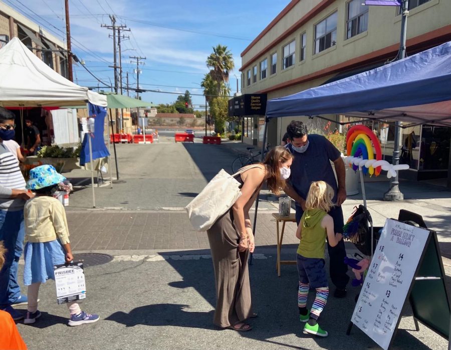 A child excitedly picks out a balloon animal at the farmers market. 