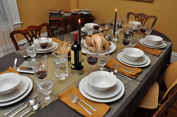 Atop a traditional Thanksgiving table lies a turkey and silverware for the upcoming feast. 