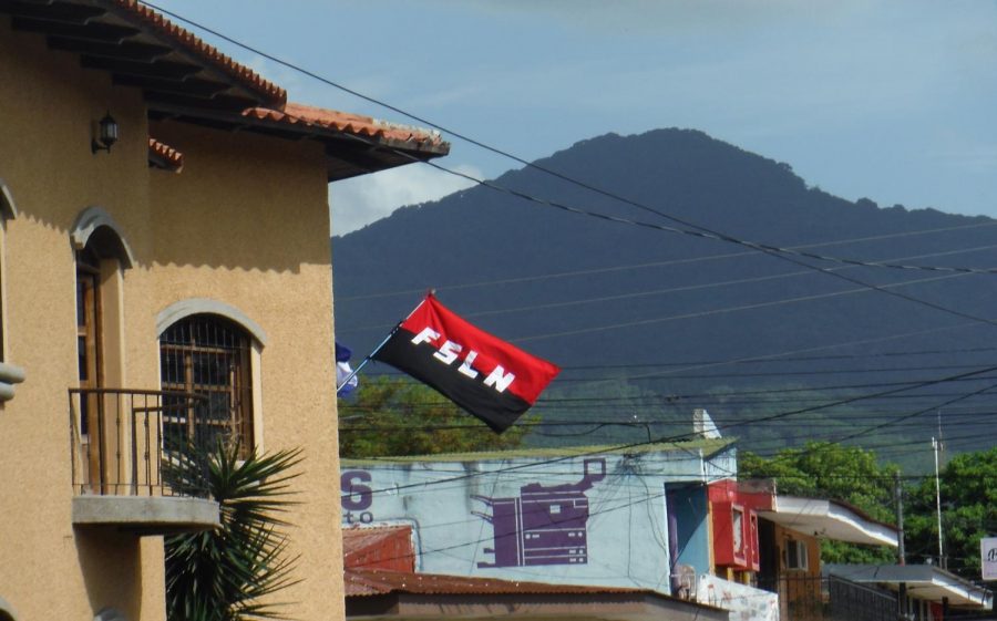 A flag of Nicaraguas ruling party, the FSLN, flies above a busy street intersection.