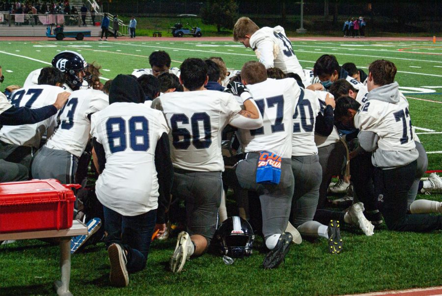 The varsity football team, one of the many sports teams at Carlmont, huddles before the start of an away game. 
