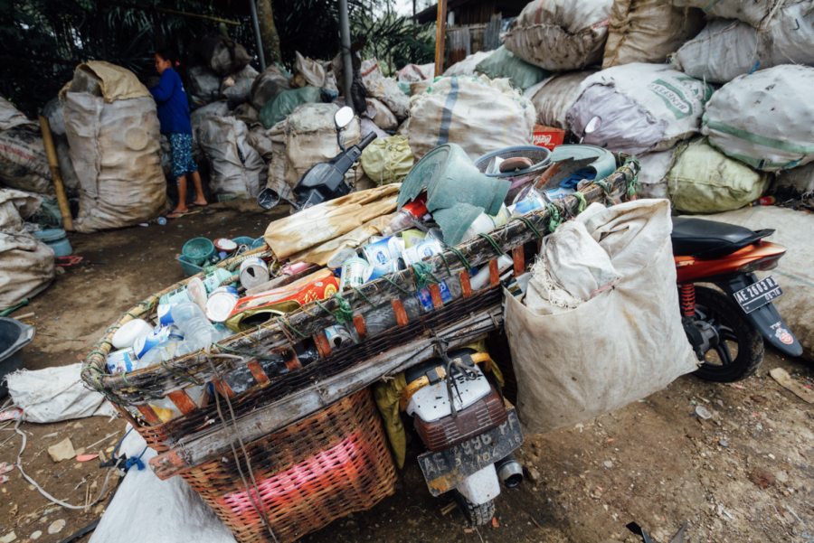 Trash pickers carry recyclable materials of value in a cart attached to a motorcycle.

