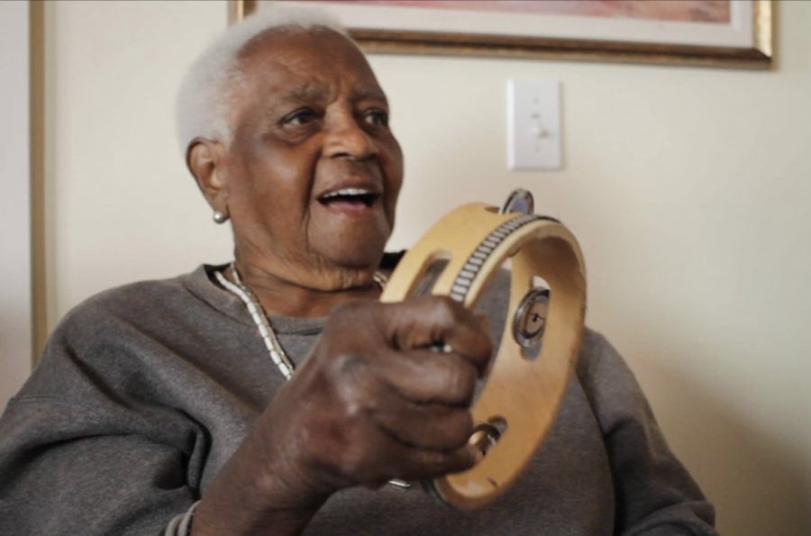 An elderly patient’s face lights up as she plays the tambourine. 
