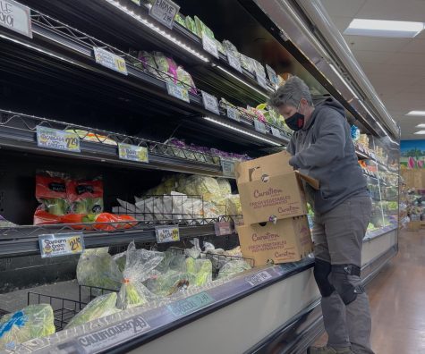  A Trader Joe's employee restocks fresh vegetables in the refrigerated foods section.