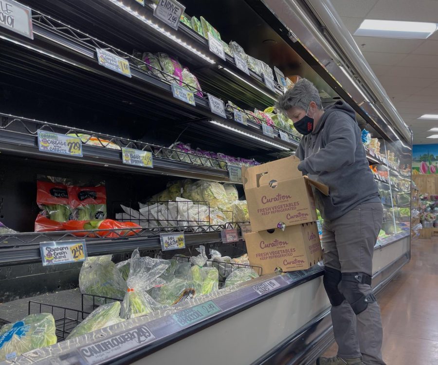  A Trader Joes employee restocks fresh vegetables in the refrigerated foods section.