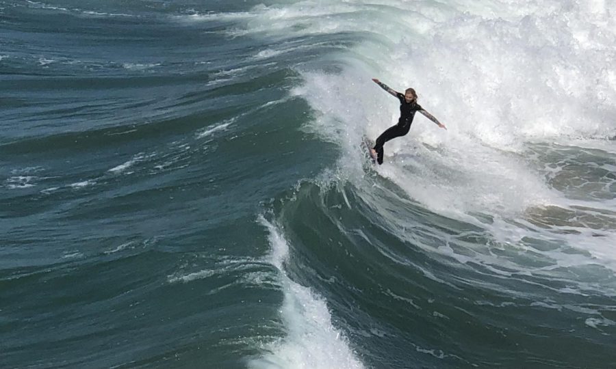 A surfer catches a big wave on a sunny day at Huntington Beach. 