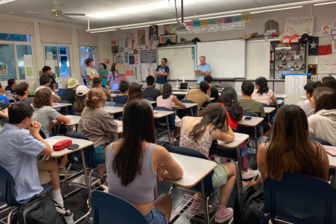 Students attend a club meeting in a classroom without air conditioning and try to remain attentive in the uncomfortable heat.