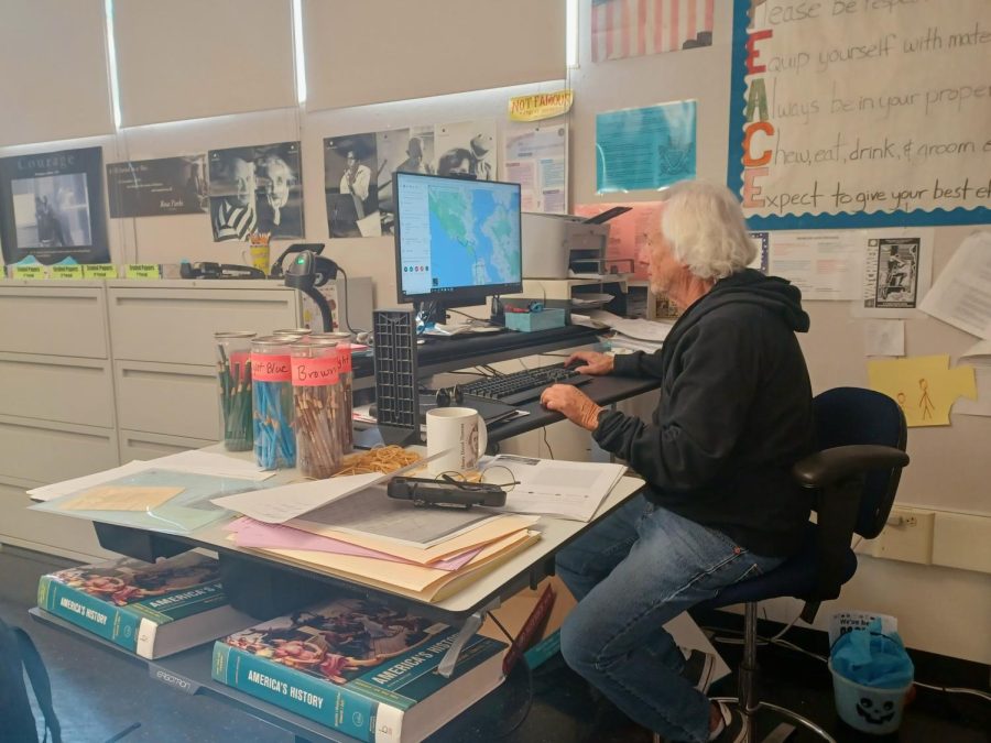 James McDowell, a substitute at Carlmont, sits at a teacher’s desk in E1. Amid the national teacher and substitute shortage, schools are working to hire more substitutes to fill in for absent teachers.