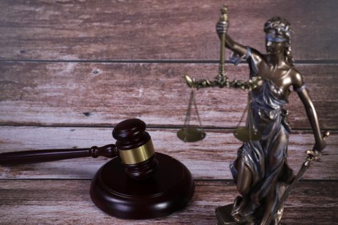 The blindfolded Lady Justice and the judge’s gavel, two representative items of the justice system, serve as a reminder of impartiality and order.