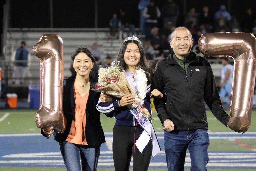 Senior Emma Wang walks with her parents in the senior night ceremony.