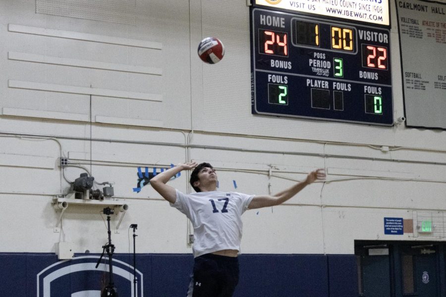 Junior middle hitter Eli Nathan jumps to serve the ball.