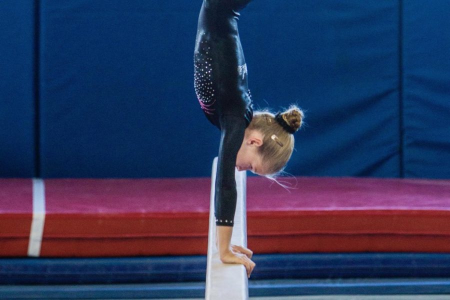 Bryce Kupbens balances a handstand on the beam at one of her first competitions.