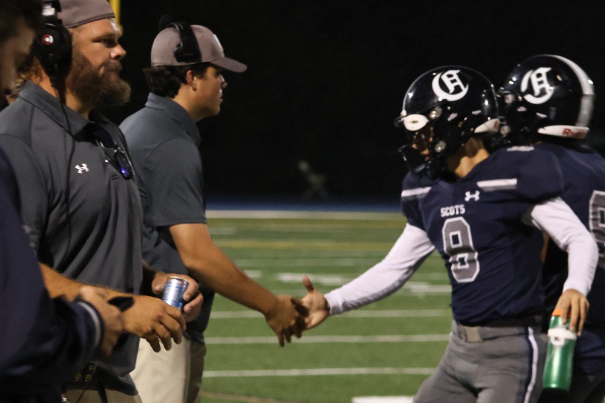 After the Scots first touchdown, senior quarterback Carlo Campobello goes to the bench as the defense runs onto the field. One of the assistant coaches high fives Campobello for the successful play the team executed. Confident in their lead, Campobello motivated the rest of the team on the bench. 