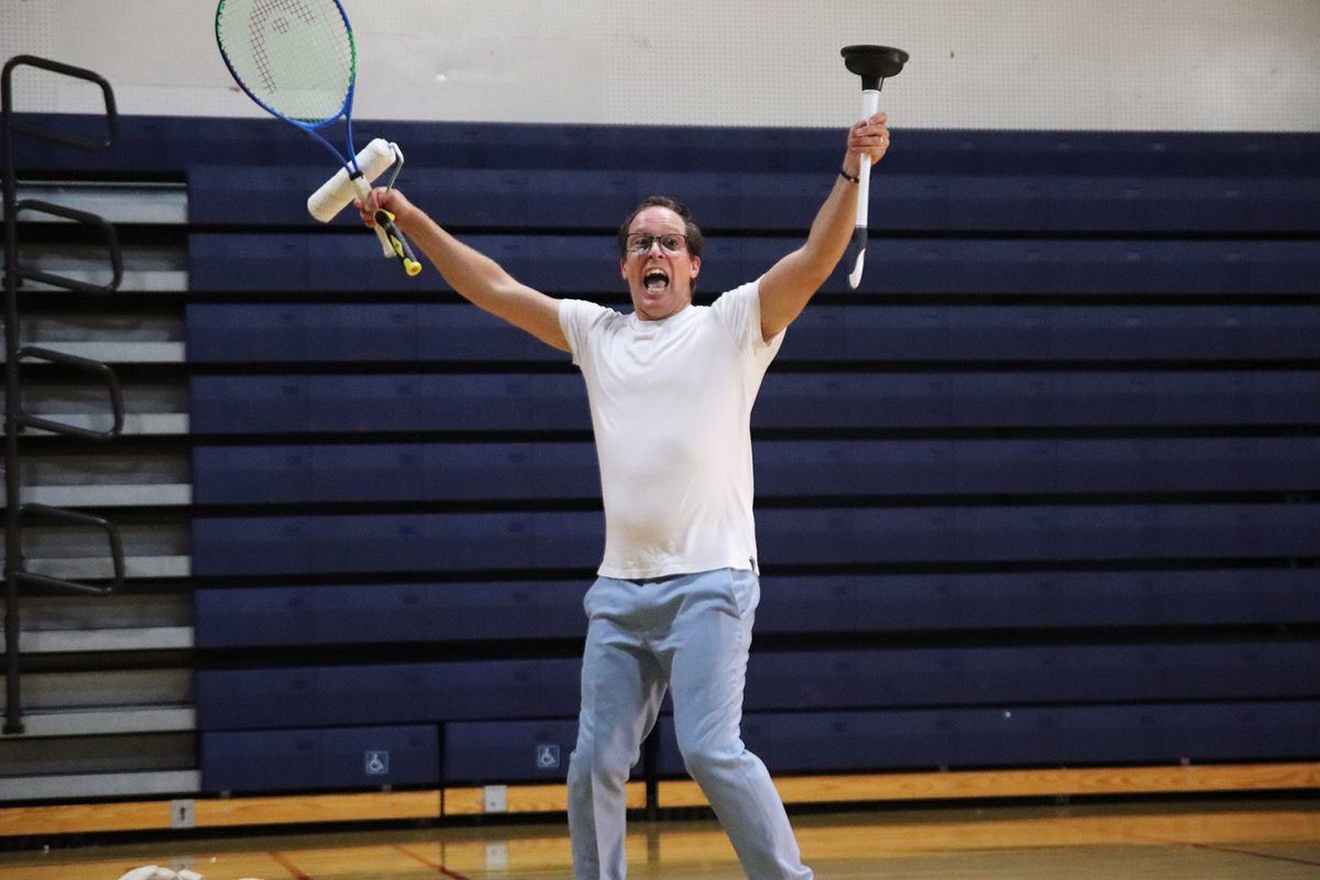 Mickey Rowe raises his hands in excitement after successfully juggling three random objects he found in the gymnasium before the assembly.