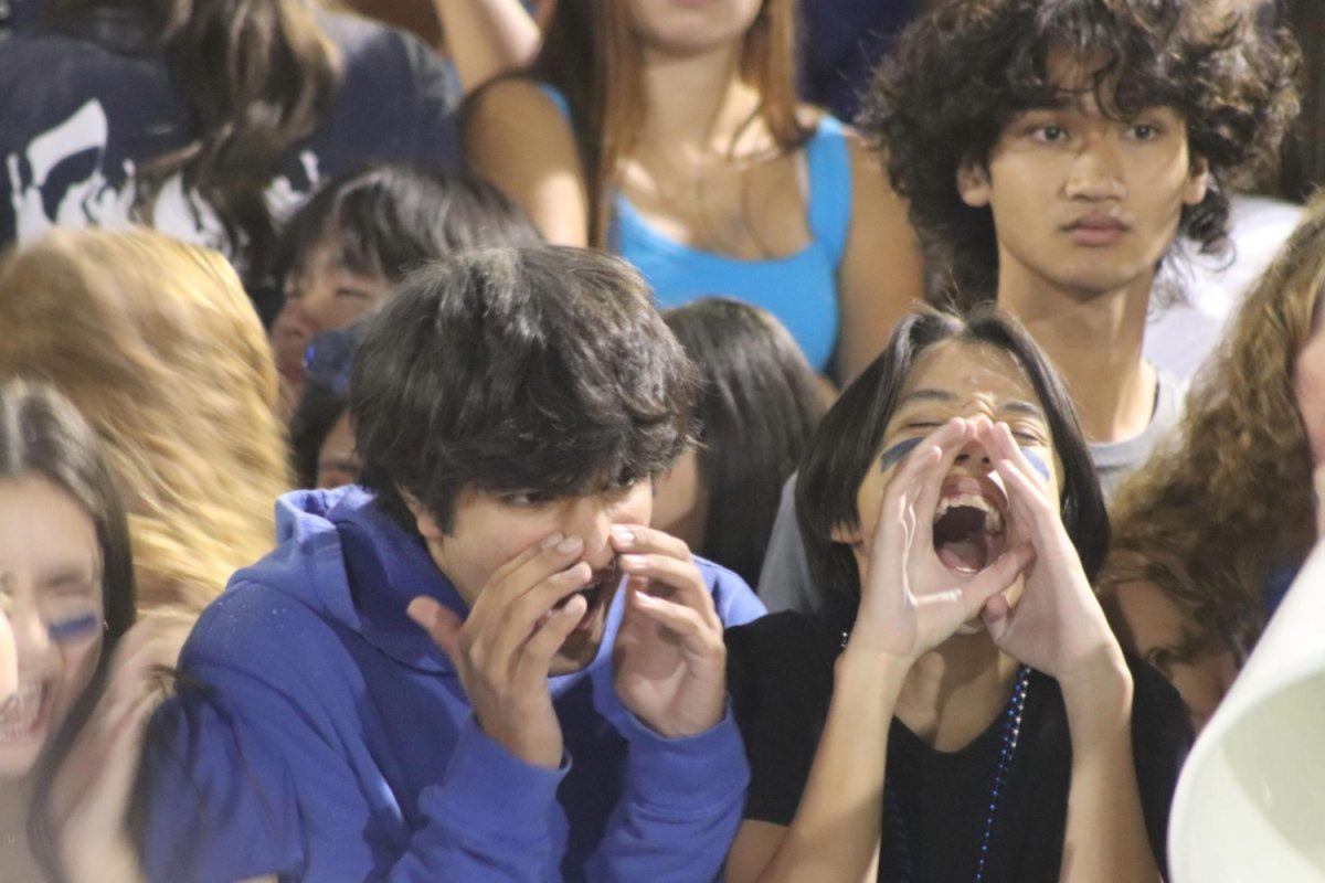 Carlmont seniors Prithvi Dixit and Marcus Tran show their support for the football team at Fridays game. After the Scots scored a touchdown, the students section went crazy and screamed for them. ASB members also used flags and cheers to get the crowd going.