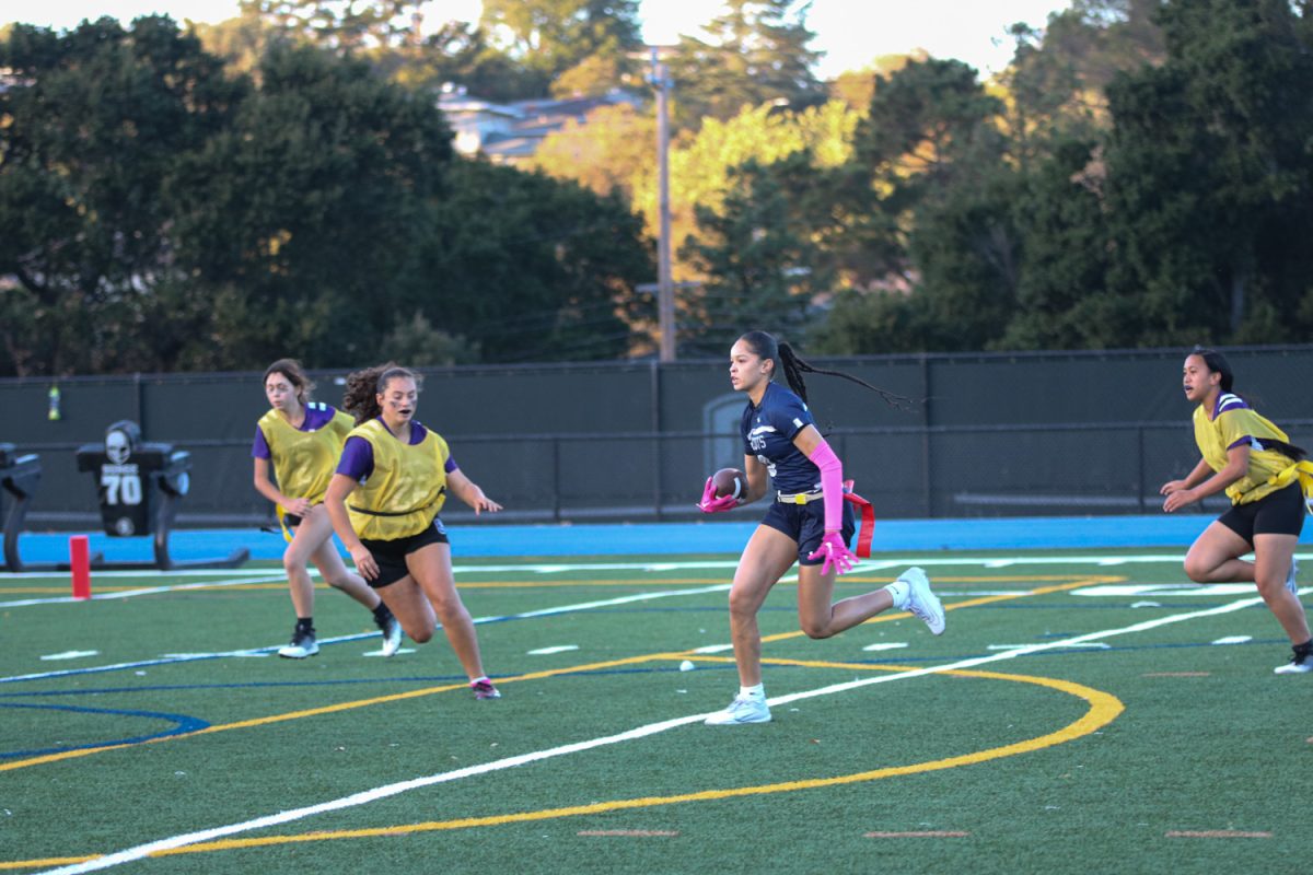 Senior Alessandra Nelson runs with the ball in her hand, trying to avoid opponents as she makes her way to the end zone.
