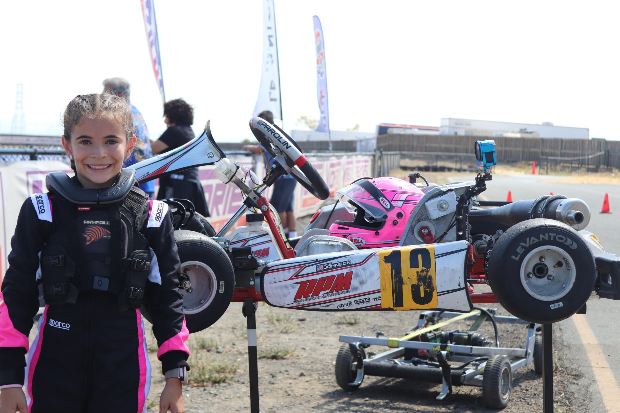Kylie Johnson with her kart, complete with a neon pink helmet. She loves the speed of karting (and beating out the boys she competes with too). “I want to get to F1 and be the first girl,” Kylie said. (Elaine Jiang)