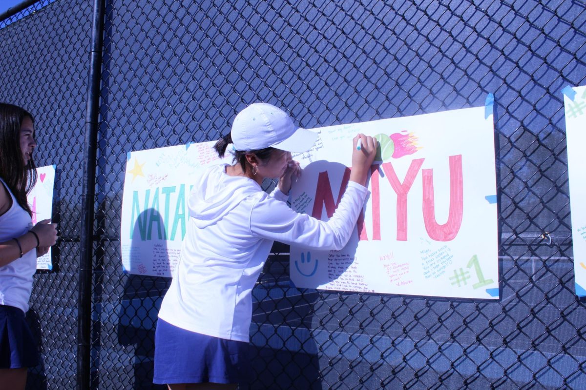 Tennis team signs posters for their seniors at the Carlmont Tennis courts. I think it was because of the hard work of everyone on the team, especially the seniors and the captains, that we were able to get number one in the league,” said sophomore Mia Ikeda.
