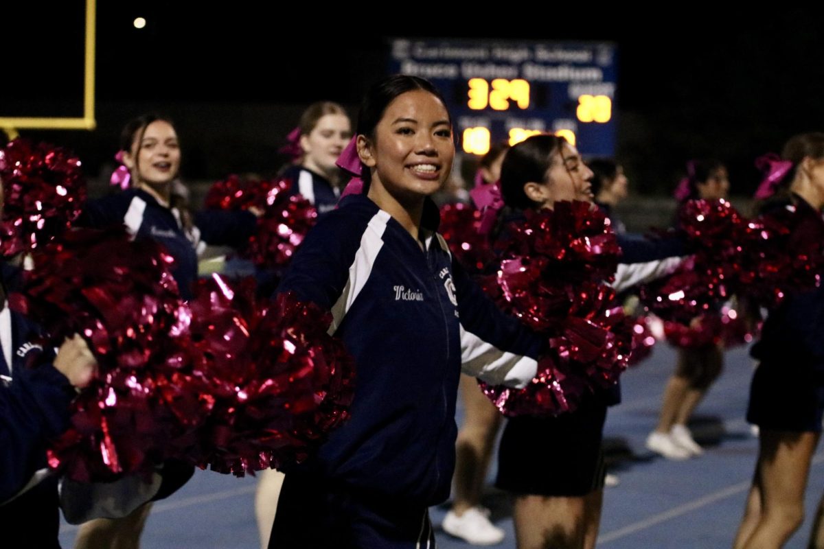 Junior Victoria Jung cheers happily for the Scots after the football team scored another touchdown. I am so proud of our performance with the mini cheerleaders. I cant wait to see the future generation of Carlmont Cheer, Jung said.