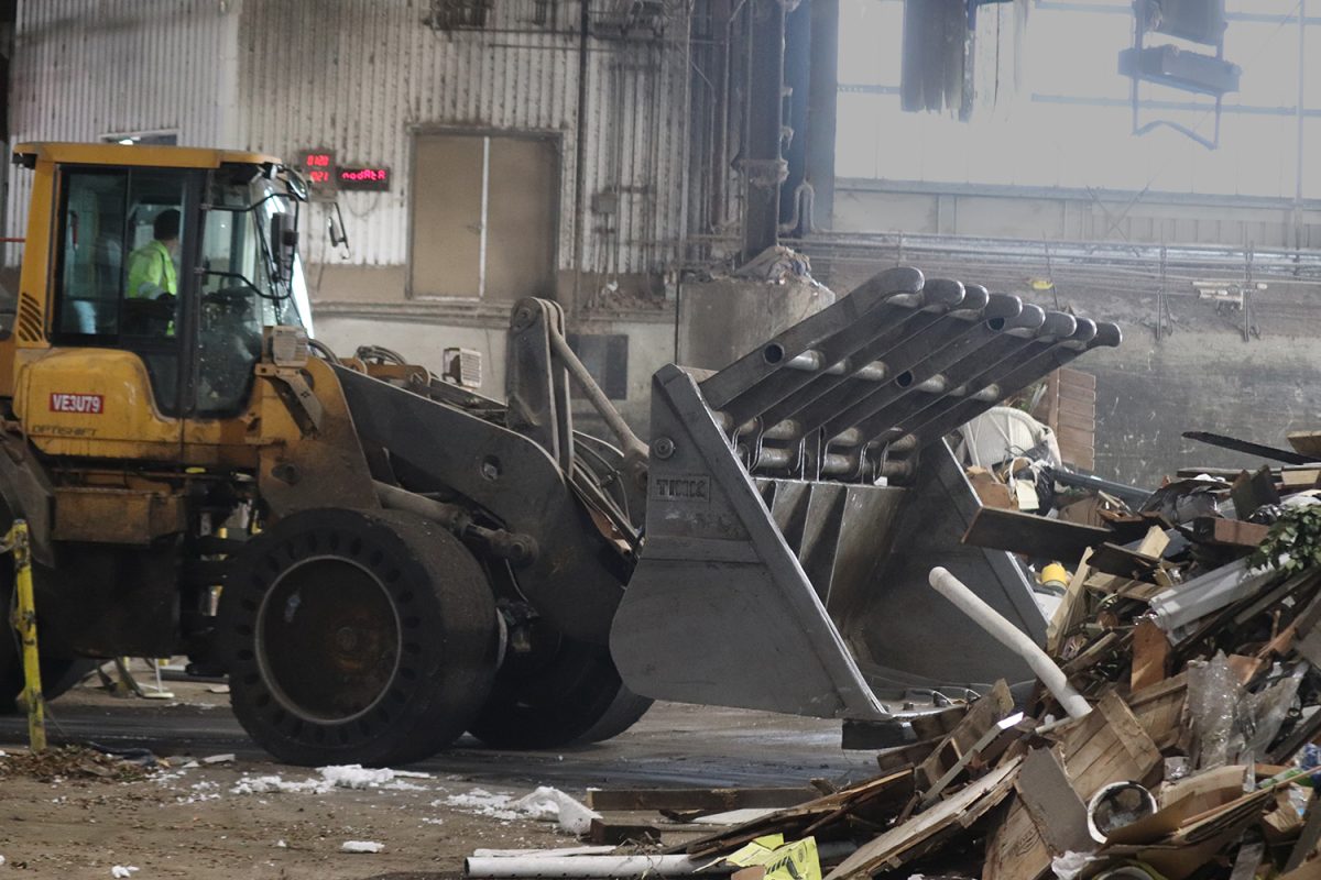 A Recology loader moves trash across the warehouse to make room for incoming loads of garbage.