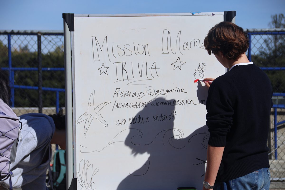 Junior Liam Gulsen draws on the Mission Marine Club sign to promote participation. Mission Marine is a club at Carlmont that focuses on conserving oceans and waterways. During lunch on Wednesday, they held trivia in the quad to spread awareness for their clubs cause. 