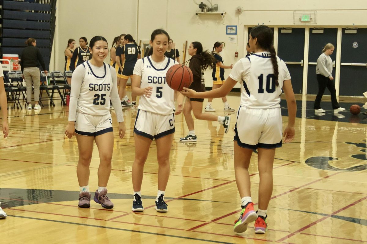 Mischa Duggal hands a ball to Charlotte Lin, who laughs with Willow Ishibashi-To. Both teams get time right before halftime ends to warm up again. The Scots were leading by 32-18 before the third quarter started.