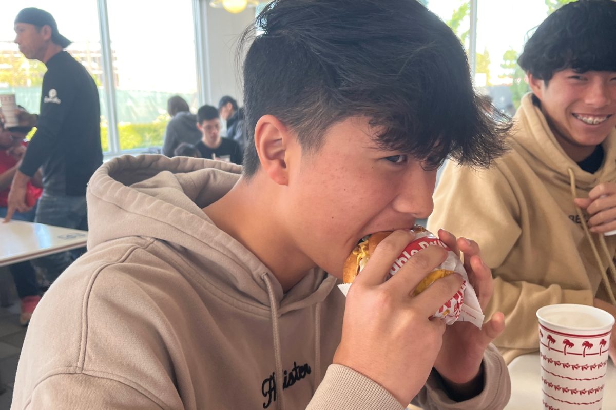 A sophomore eats his In-N-Out Double-Double Animal Style. High schoolers love the affordable prices at In-N-Out making it a trendy place to hang out with friends.