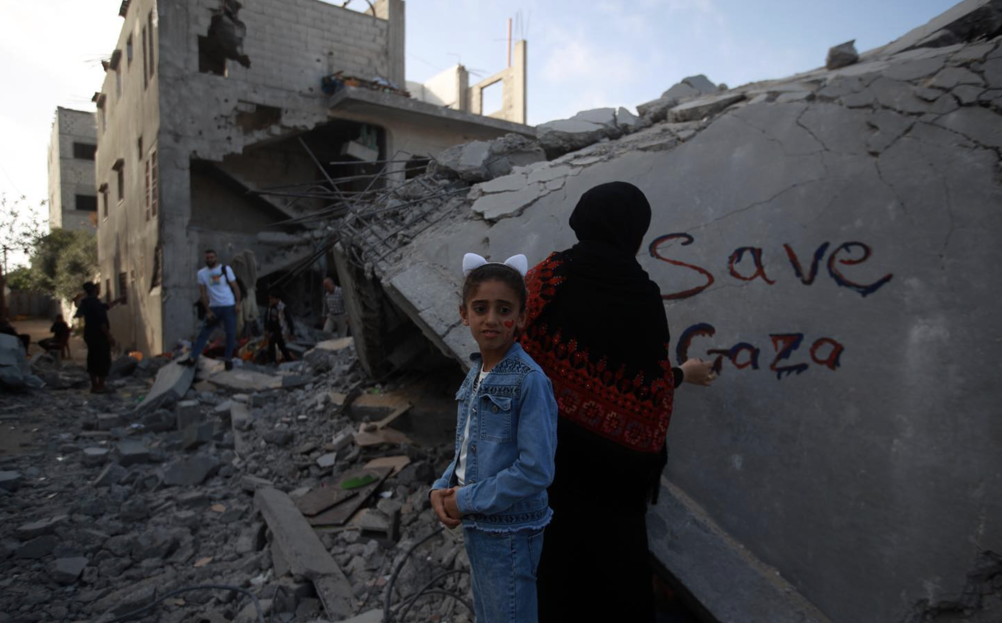 Palestinians paint Save Gaza on a section of a destroyed building in May, 2023.