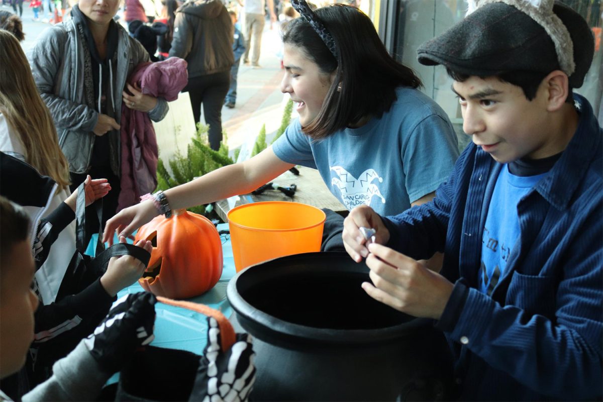 Members of the San Carlos Childrens Theater (SCCT), Piper Nguyen and Nathan Malamy, give candy to trick-or-treaters outside of a restaurant, playing a large role in community engagement. “Its important to have community events so that the people of the town can get familiar with each other, Nguyen said. 