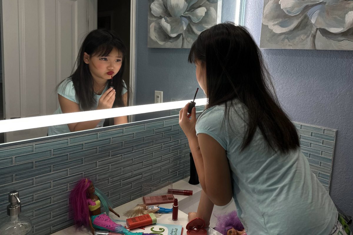 A second grader experiments with makeup and toys. The age where young girls will begin applying makeup is getting younger due to the influence of the internet. 
