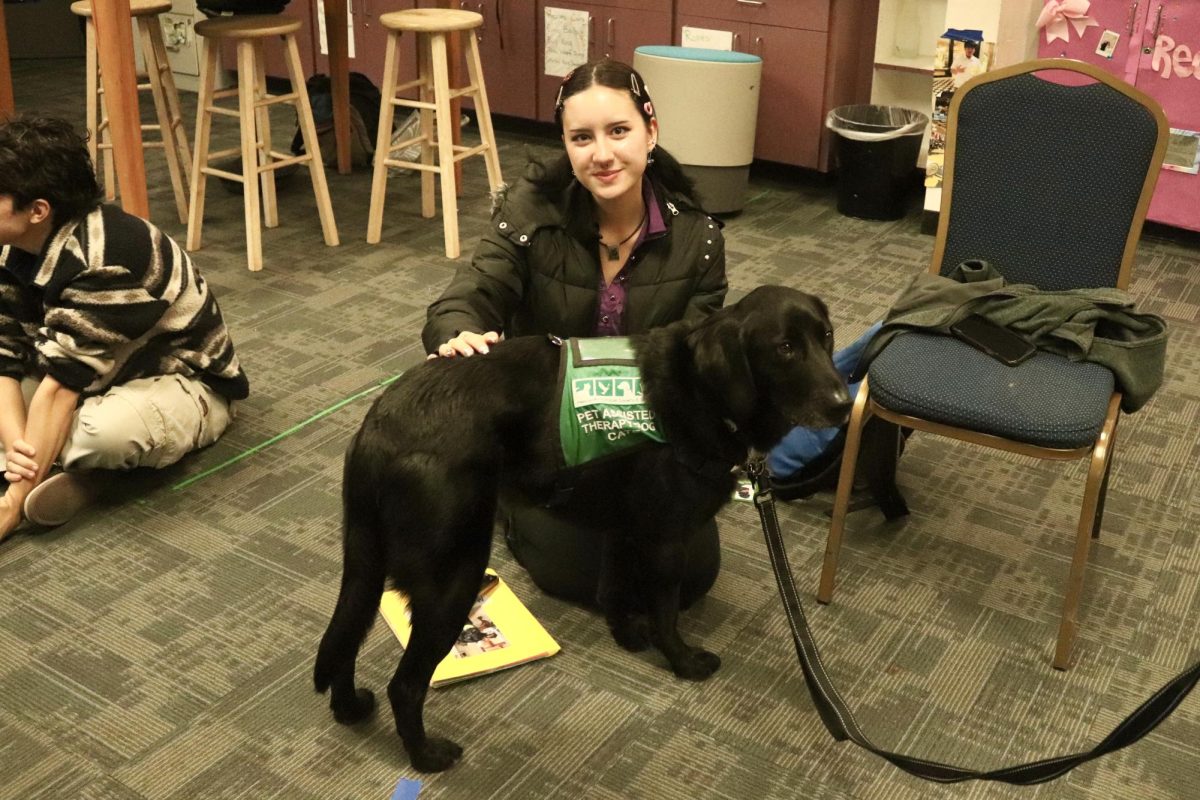 ASB representative Elisa Lou-Wimmer sits with Cate, a black labrador golden retriever mix. “It’s so calming to be around these dogs. They are really well-behaved and so cute,” Lou-Wimmer said. 