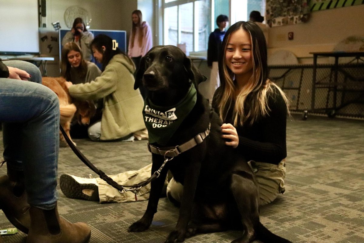 Jazzlin Yee smiles at Sadie, a black lab. Despite being local resident’s personal dogs, they have to get certified and pass many tests before they can become a therapy dog. “The dogs were very cute and it was a great way to de-stress before finals,” Yee said.