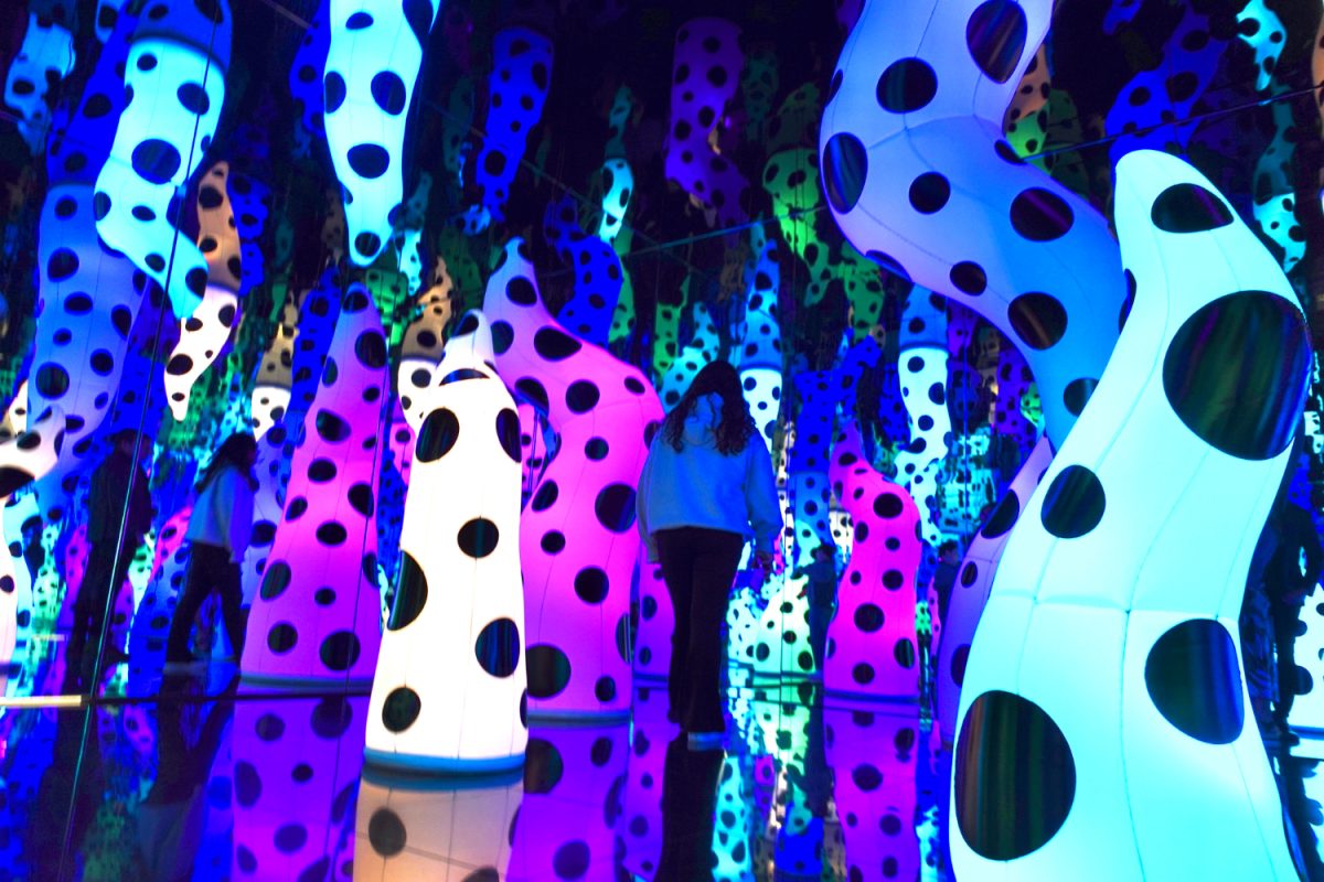 A girl is walking through the disorienting exhibit by Yayoi Kusama.