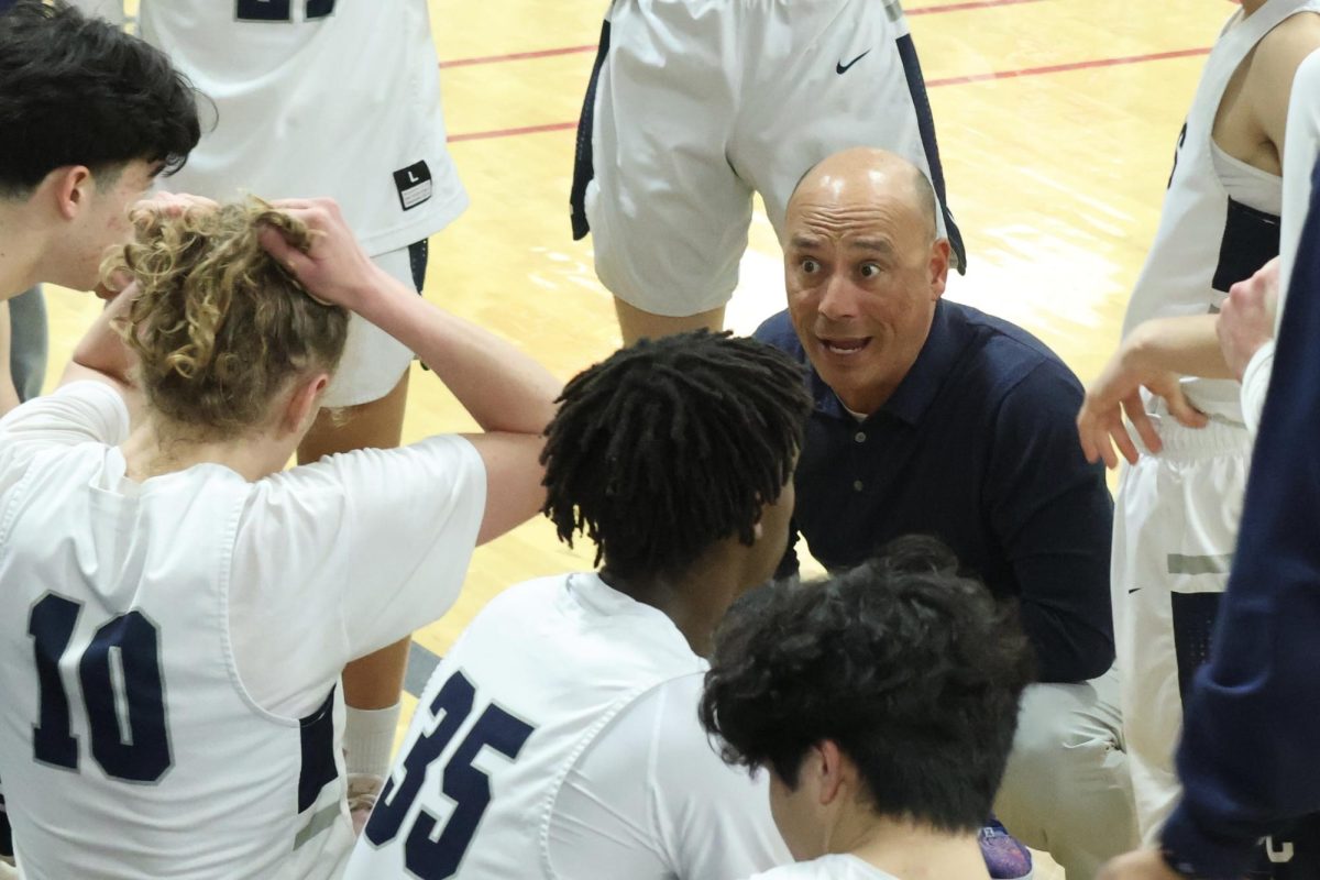 Carlmont players huddle around head coach Ron Ozorio during a timeout. “Coach Ron gives us a lot of constructive criticism and ways to improve our gameplay during these,” Ngo said. “He encourages us to return to the court and give it our all.”