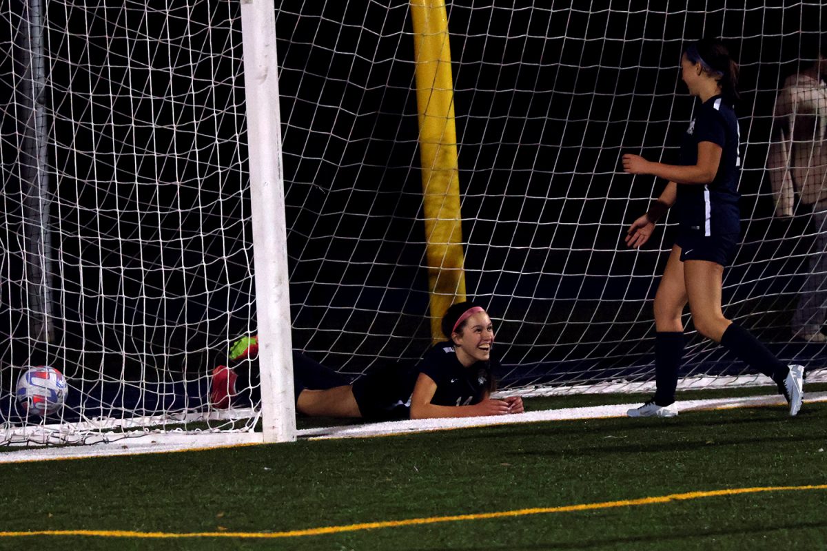 Lopez smiles at her teammate from inside of the goal. Lopez chased after a cross by Kumer, beating the goalie in a one vs. one. She scored the games final goal before sliding into the net on her follow-through.