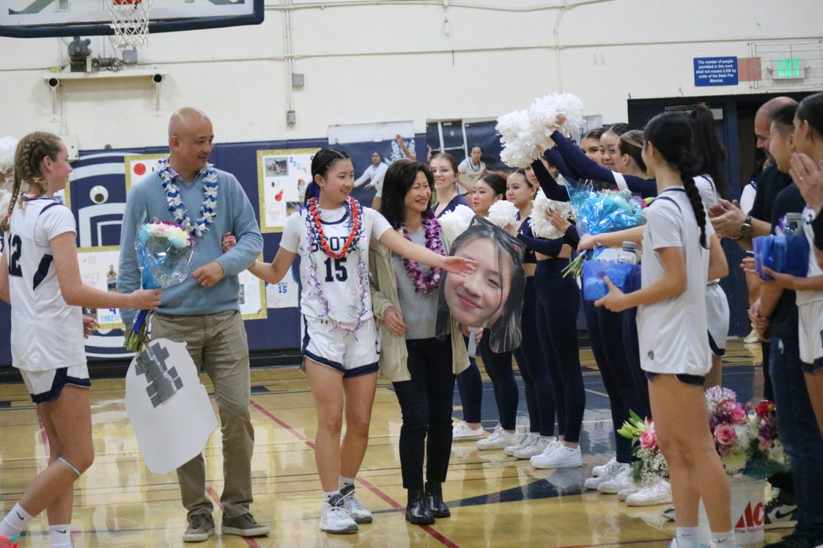 Senior Sydney Tao walks through an array of people with her mom and dad, accepting gifts and flowers from her fellow teammates.
