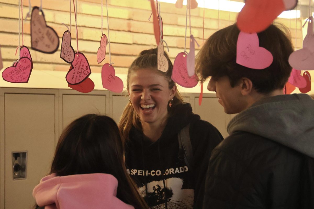 Junior Addison Mann laughs and smiles with her friends while searching for her heart in C-Hall. The personalized hearts are a big attraction for Carlmont students, leaving the halls packed with people during lunch. The written messages on each heart leave students with grins and laughs.