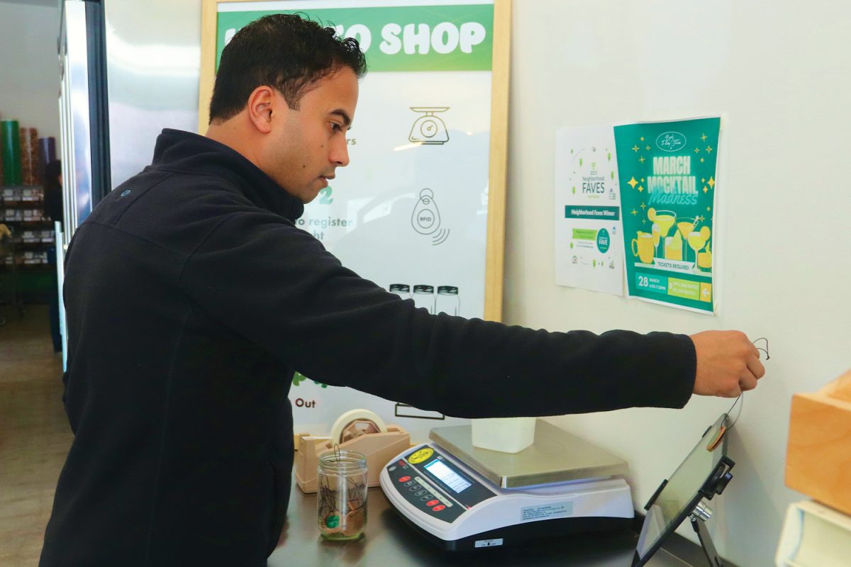 Jason Desouza, a Byrd’s Filling Station customer, scans a chip to mark his container. Customers weigh their container and mark it with a chip so they pay for the products weight during checkout. The store has three weighing stations with posters that show instructions on completing the process.