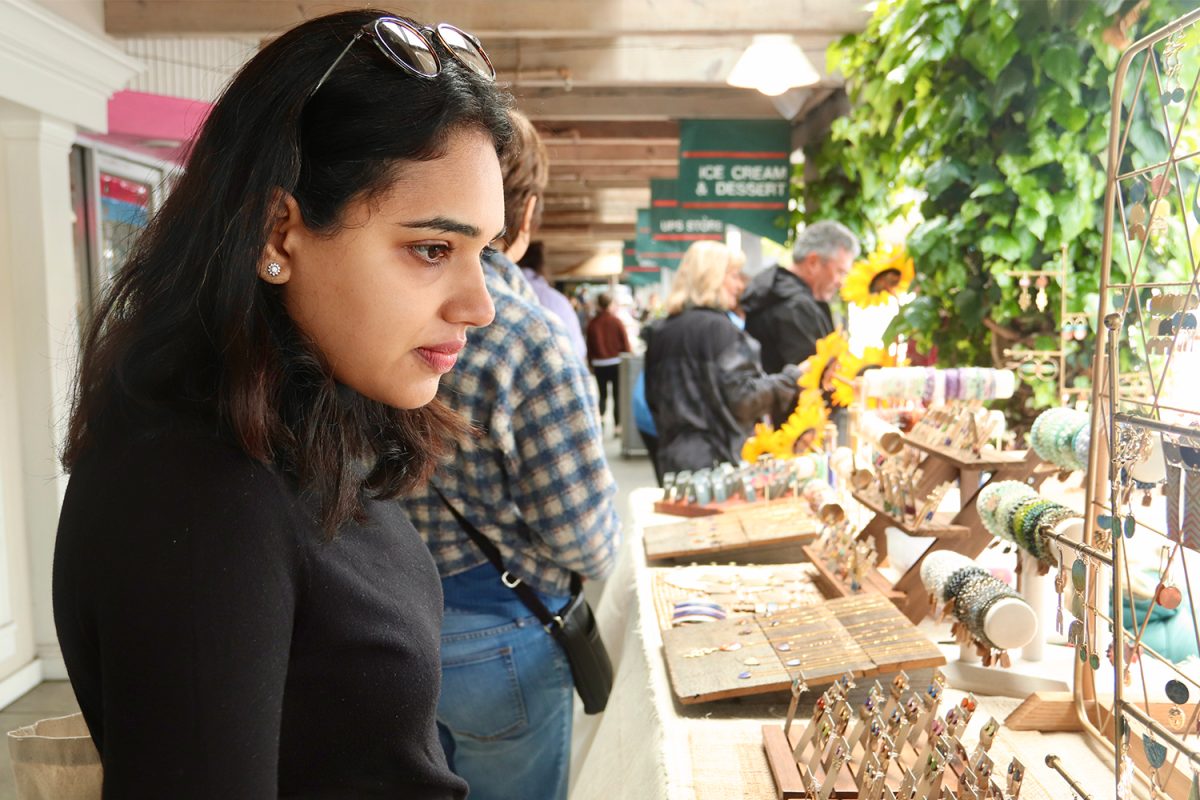 A passerby looks at a pair of Chelsey Greene Studio earrings. She also admired the handmade bobby pins and necklaces at the stand. Other vendors were selling jewelry, but a unique aspect of Greenes stand was that she offered color customizations for her jewelry, where customers could request a different color on the same style of earrings they liked. 