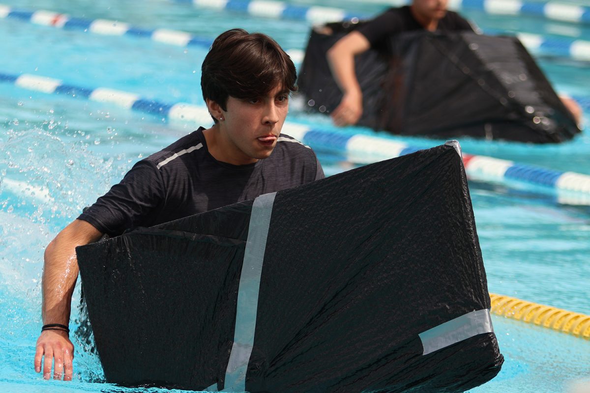 A geometry student concentrates as he prepares to reach the end of the pool. Students had to bring their boats to the other side of the lane before turning around. The first couple of students to reach the end of the pool qualified for the semifinals.