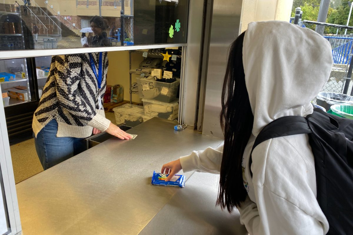 Sophomore Sara Ho purchases a cinnamon Pop-Tart, a recently added snack item, from the student store. The addition of the Pop-Tart is part of a larger effort by the Parent-Teacher-Student-Association (PTSA) to increase revenue and options for students at the store. 