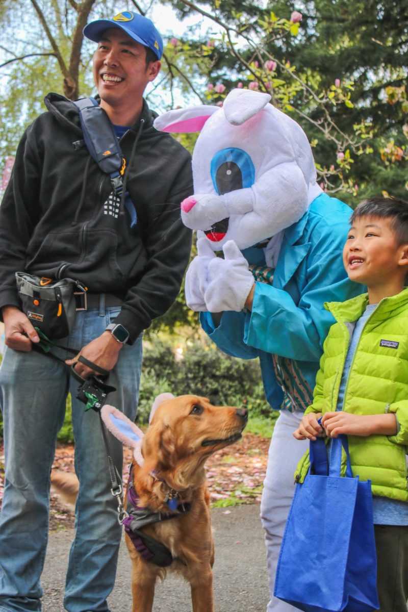 A family and their dog eagerly taking a photo with the easter bunny. Outside the main egg hunt areas, photo booths were set up for families to take pictures with costumed bunnies.