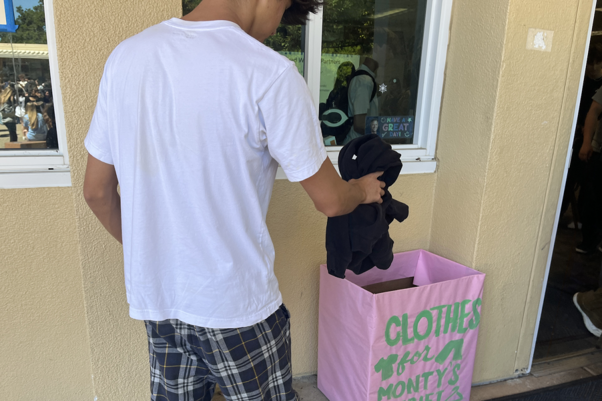 A Carlmont student places a piece of attire into a donation bin outside of the ASB room. We get all different kinds of clothes, said Maddy Ho, a Carlmont freshman.