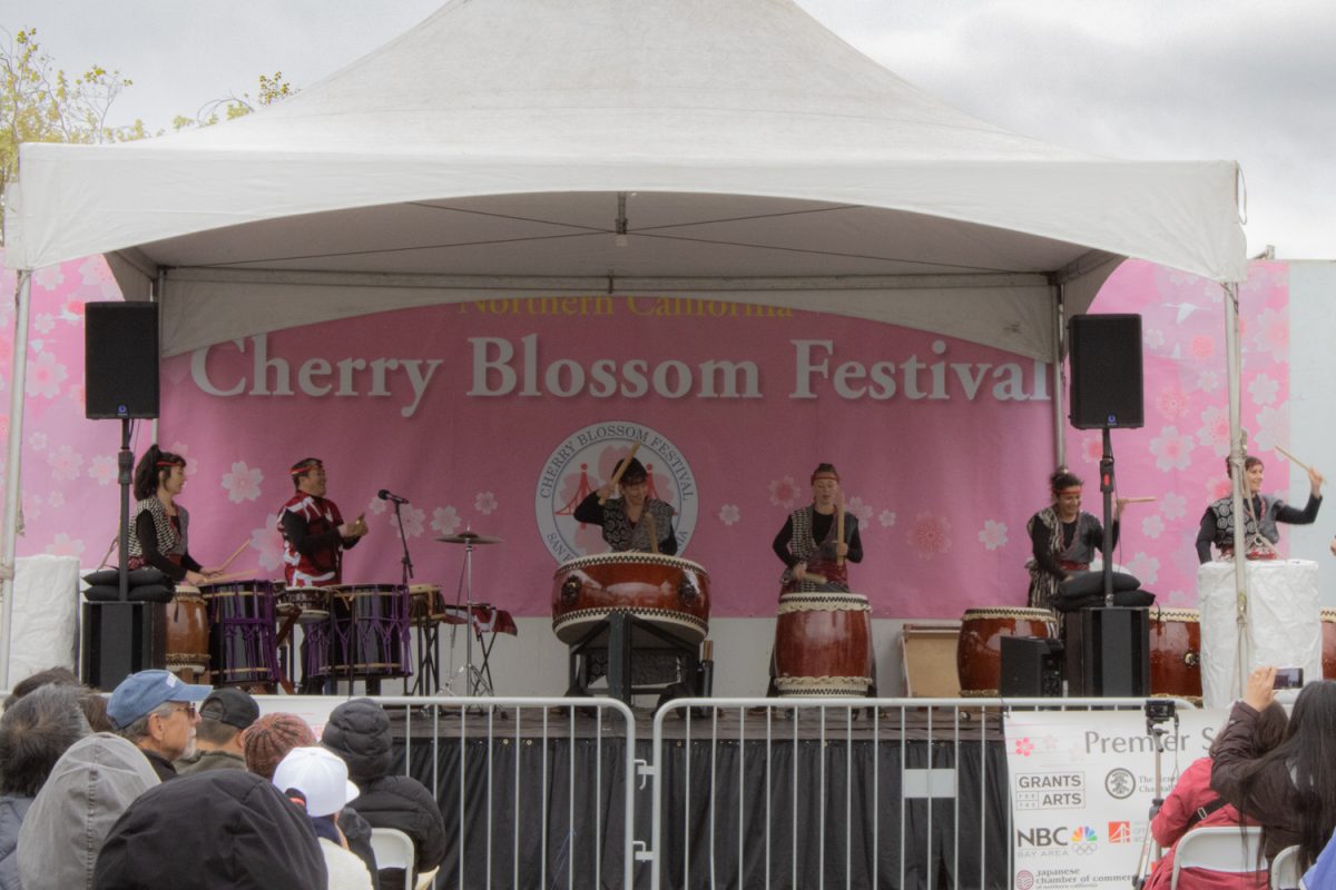 At the opening ceremony of the 57th annual Northern California Cherry Blossom Festival, attendees watch a taiko performance on the Peace Plaza Stage. The festival showcases various aspects of Japanese culture and is open to all.