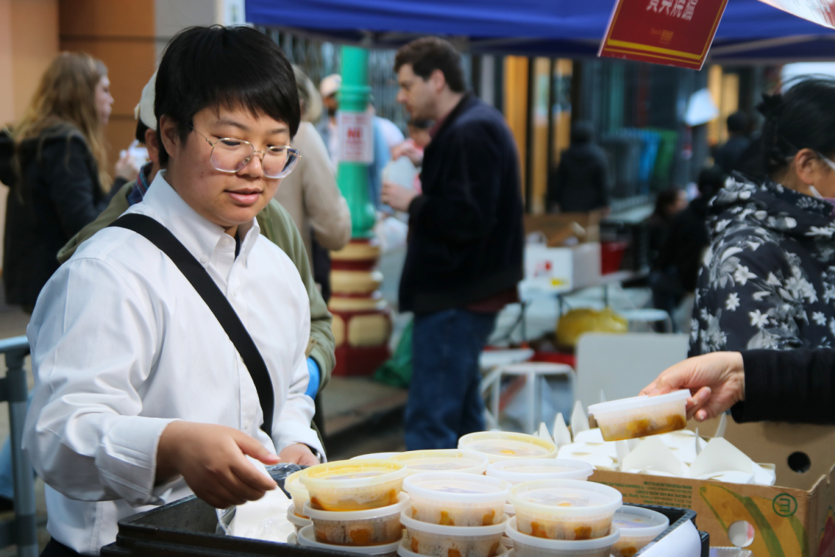 A woman at the New Golden Daisy restaurants booth helps a customer pick out her order. Everything they sold was $5 and packaged in individual containers. Friends and relatives of the vendors delivered fresher, packed food to their respective booths because the vendors couldnt cook on-site.