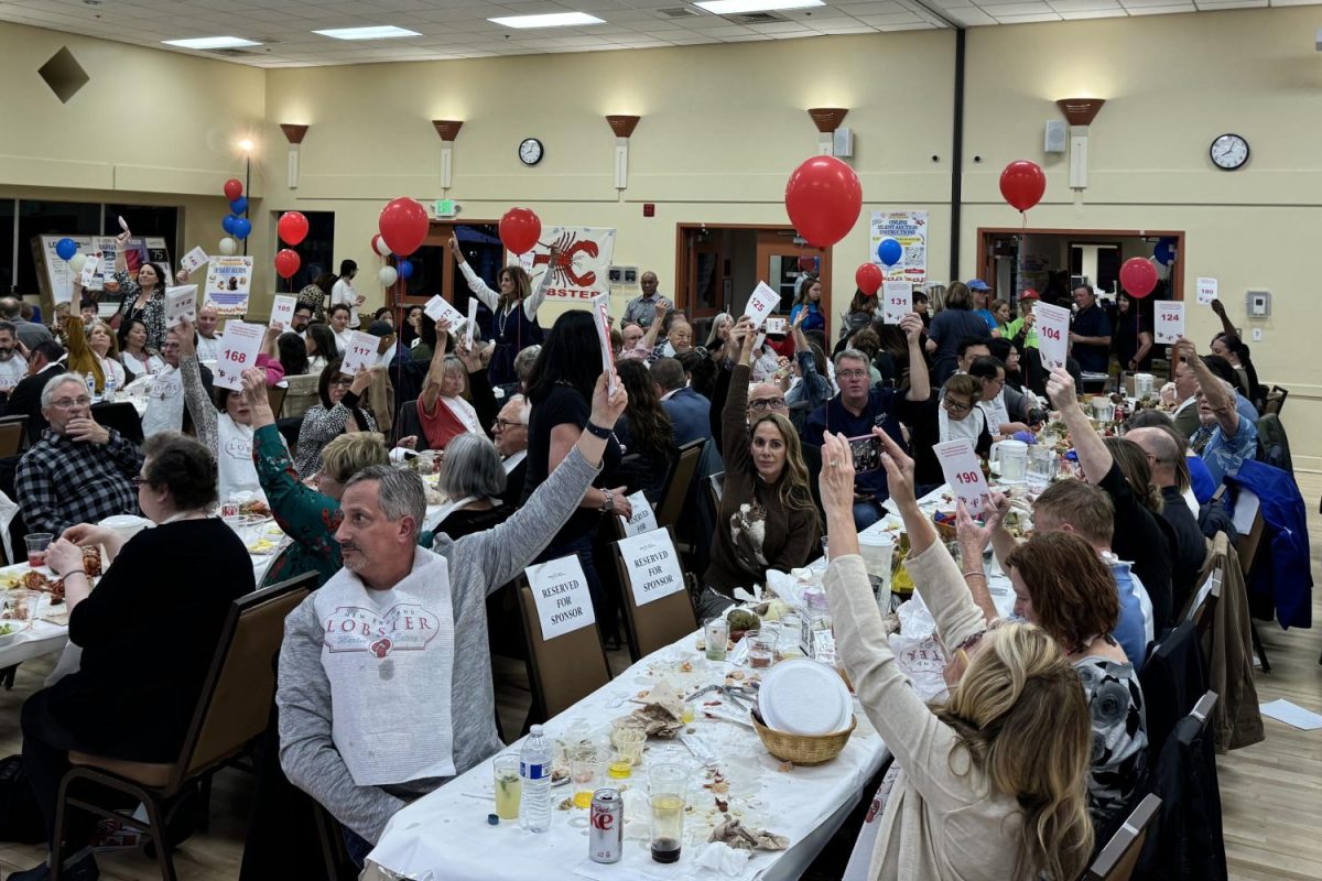 Attendees+of+the+2024+LobsterFest+fundraiser+raise+their+paddles+to+bid+in+an+auction+held+during+the+event.+%E2%80%9CEveryone+was+enjoying+the+food%2C+and+it+was+my+first+time+seeing+a+silent+auction%2C+so+it+was+a+really+cool+experience+to+see+so+many+people+bidding%2C%E2%80%9D+said+Victoria+Jung%2C+one+of+the+volunteers+at+the+Lobster+Fest.