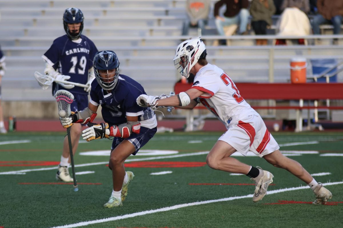 Senior Jacob Tom runs the ball down the field after winning a face-off. With quick pressure from a Burlingame defender, Tom rounded the corner and looked for a possible shot or open teammate. Despite hard contact from the opponent, Tom maintained possession and control of the ball.