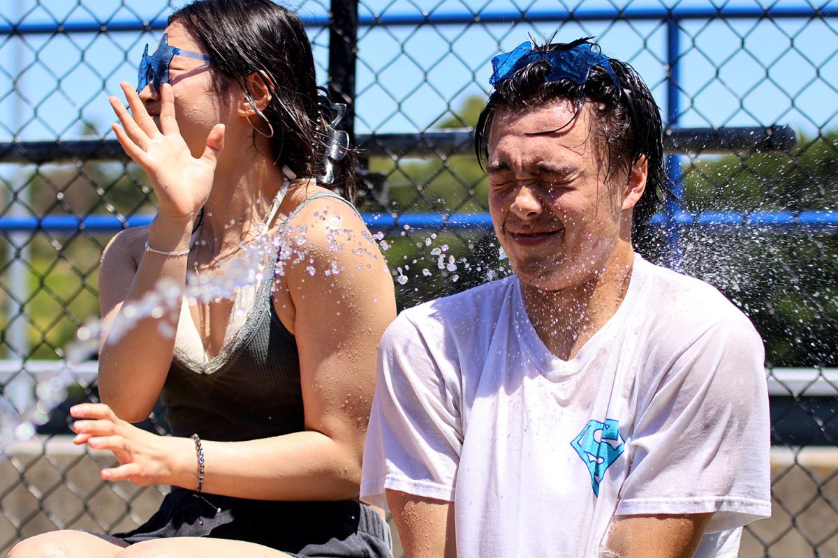 Senior Nicholas Tolod winces at after being sprayed with water as part of the Splash a Senior booth. Carlmont Associated Student Body (ASB), club members, and business classes set up booths in the quad on Friday. Students of every grade stopped by this water booth to shoot water at several seniors sitting in a row. 
