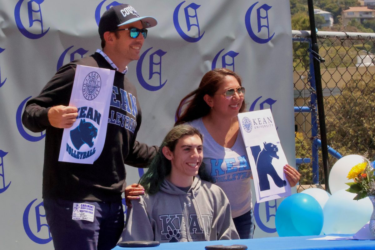Sean Murphy smiles with his parents as they hold up signs in support of his college commitment. Murphy will be attending Kean University in the fall to continue playing volleyball and to study exercise science. 