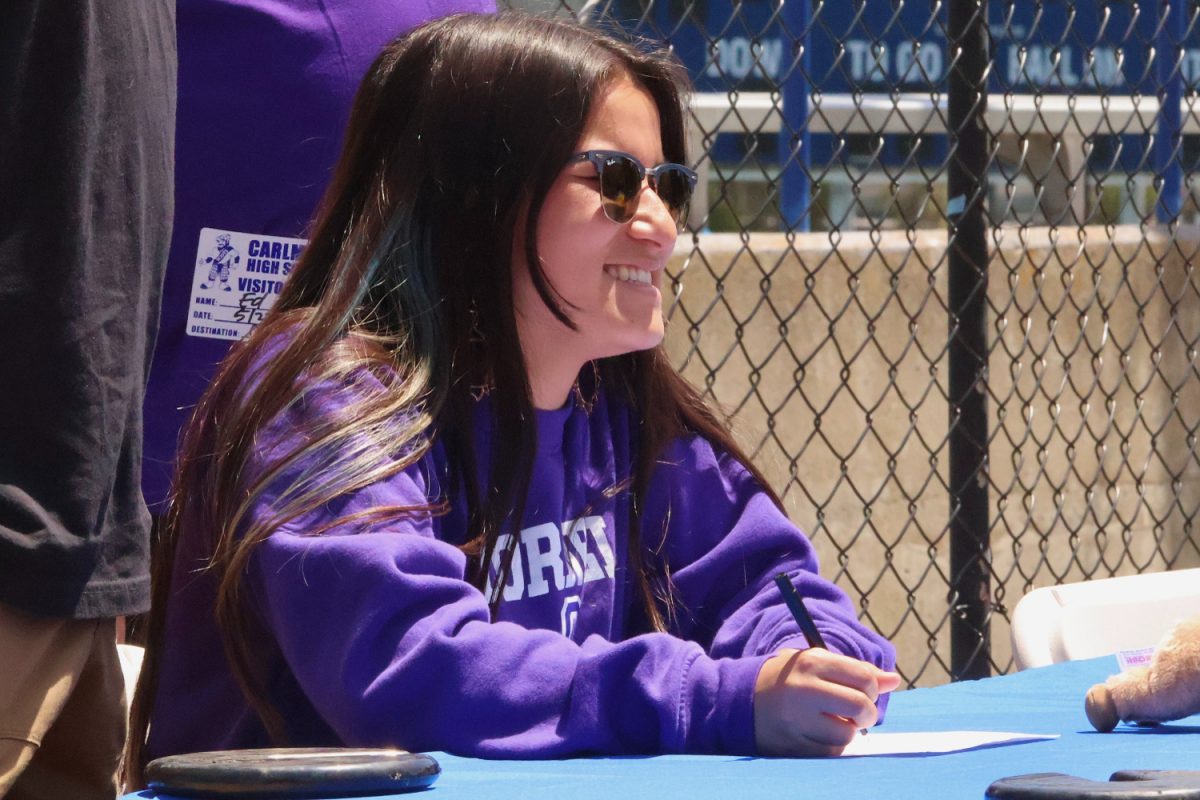 Leila Velez smiles as she signs a paper representing her college commitment. Velez will be studying kinesiology and playing Division III lacrosse at Cornell College. “I’m definitely excited to head into another 4 years of playing lacrosse at the higher level,” Velez said.
